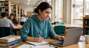 A woman writing on a pad with a laptop in front of her.